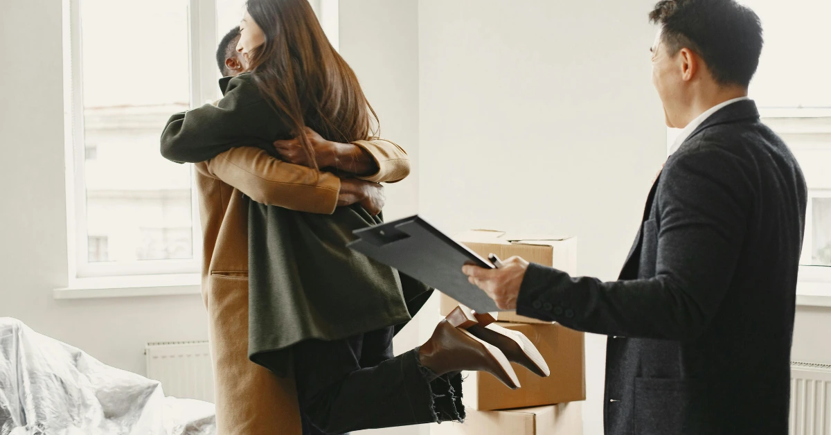 A Couple Hugging Each Other Beside A Real Estate Agent (1) A Couple Hugging Each Other Beside A Real Estate Agent (1)