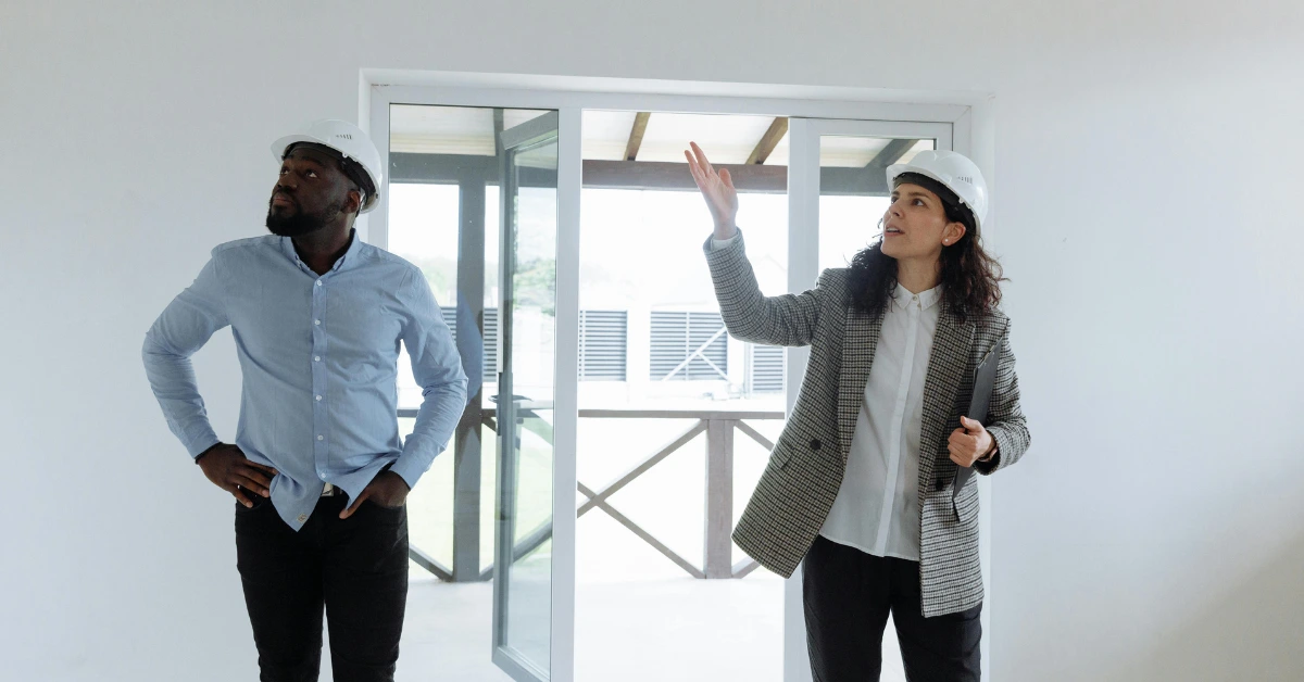 A Real Estate Agent Wearing Hard Hat Showing House to a Buyer A Real Estate Agent Wearing Hard Hat Showing House to a Buyer